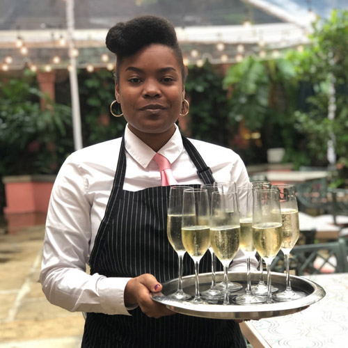 Waitress with tray of wine glasses in the courtyard