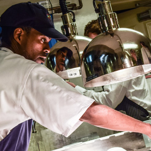 Member of kitchen staff working on preparing a dish